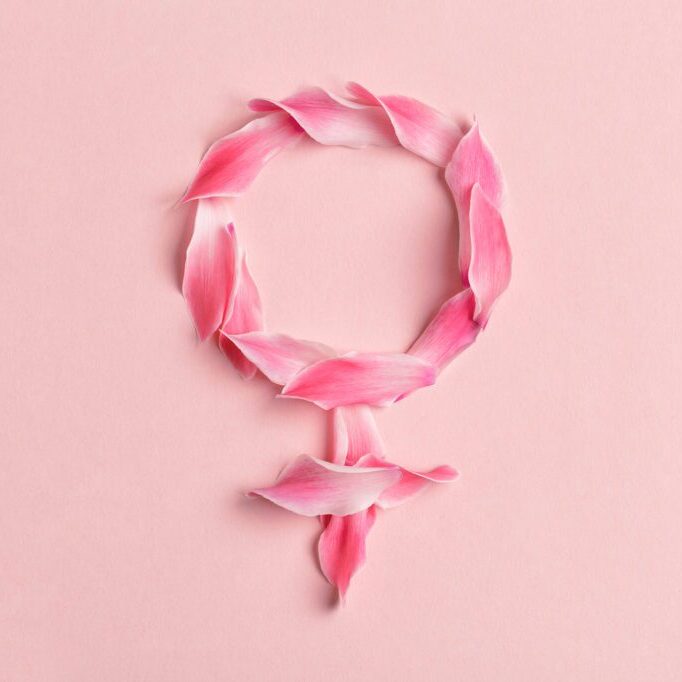 Gender Venus symbol made of beautiful flower petals on candy pink background, woman sign